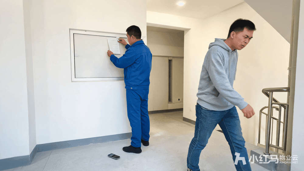 物业工作人员在小区楼道贴催缴通知业主不耐烦绕行